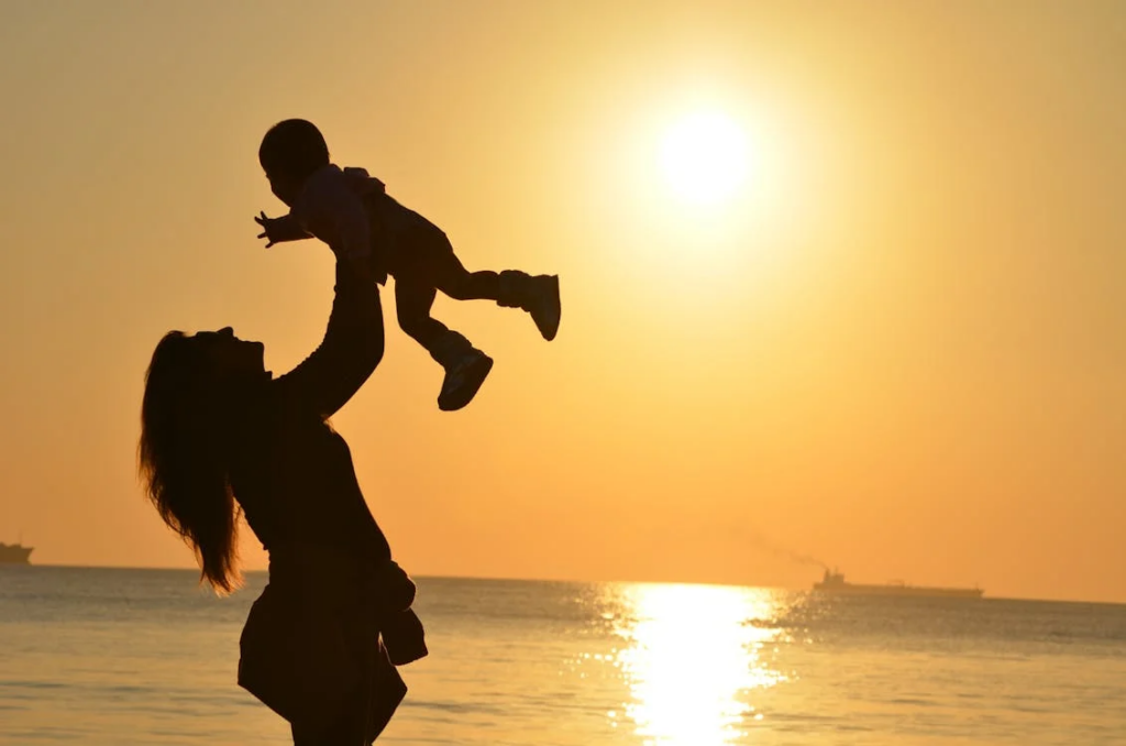 a mother playing with her baby during the sunset