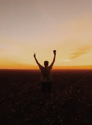 A person with hands up in a field