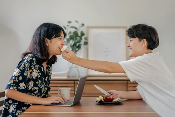 a person feeding another fruit