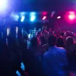 People dancing in a nightclub with flashing lights and possible drug use.