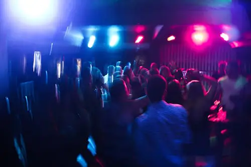 People dancing in a nightclub with flashing lights and possible drug use.