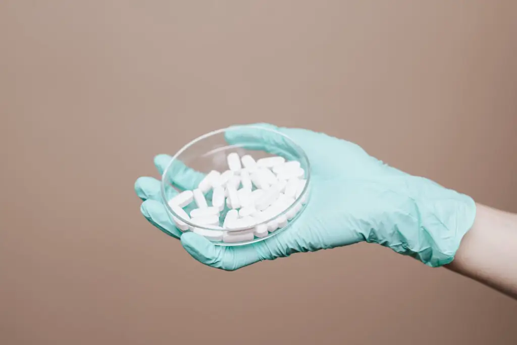 A close-up of a person holding pills in their hand.