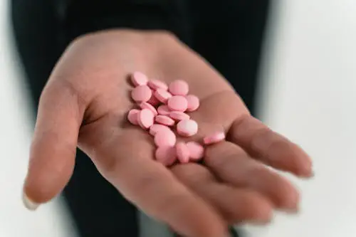 A woman holding a handful of pills in her palm.